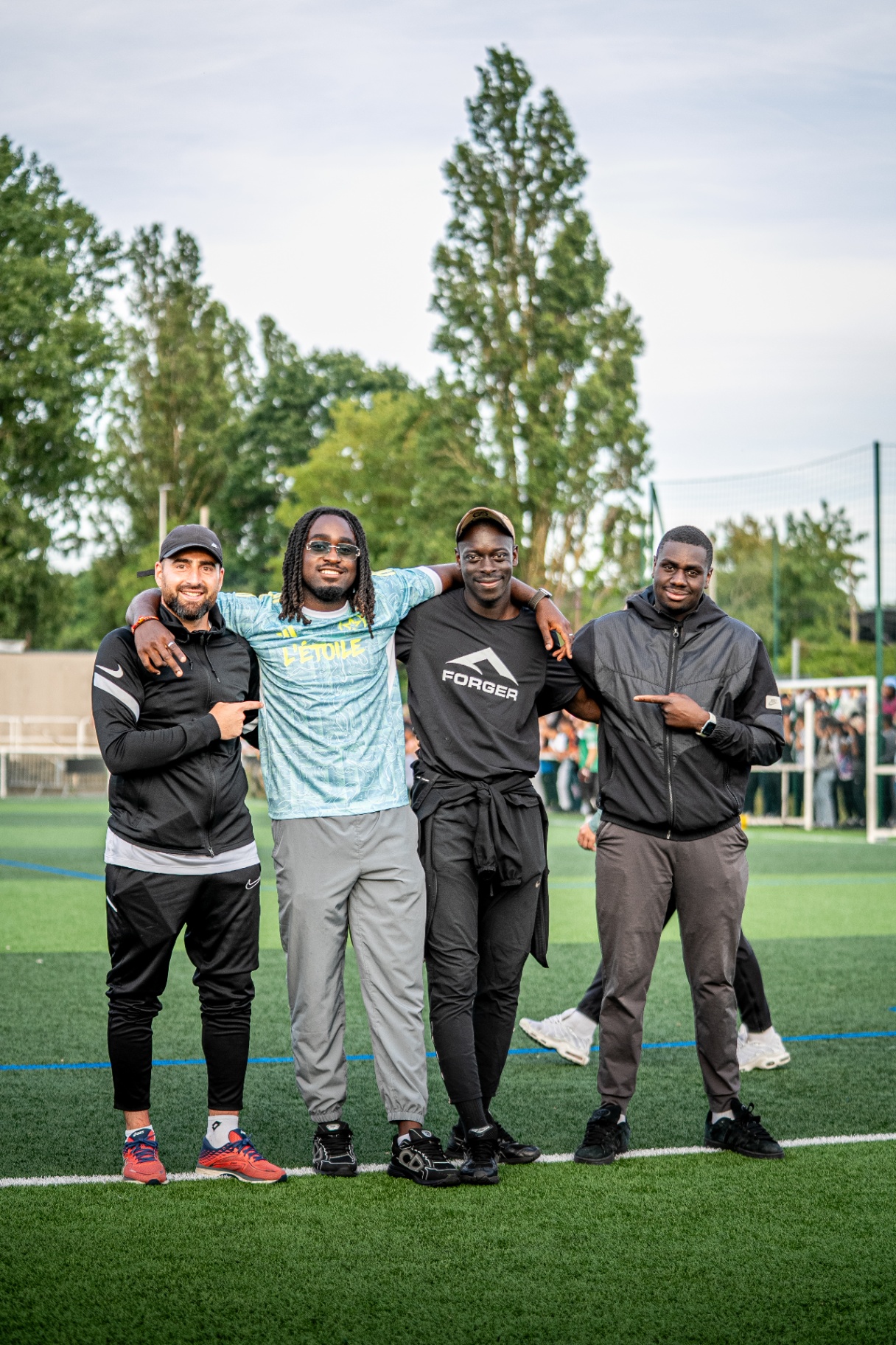 Quatre membres de FORGER Paris posant sur la pelouse, l'un portant un t-shirt FORGER noir