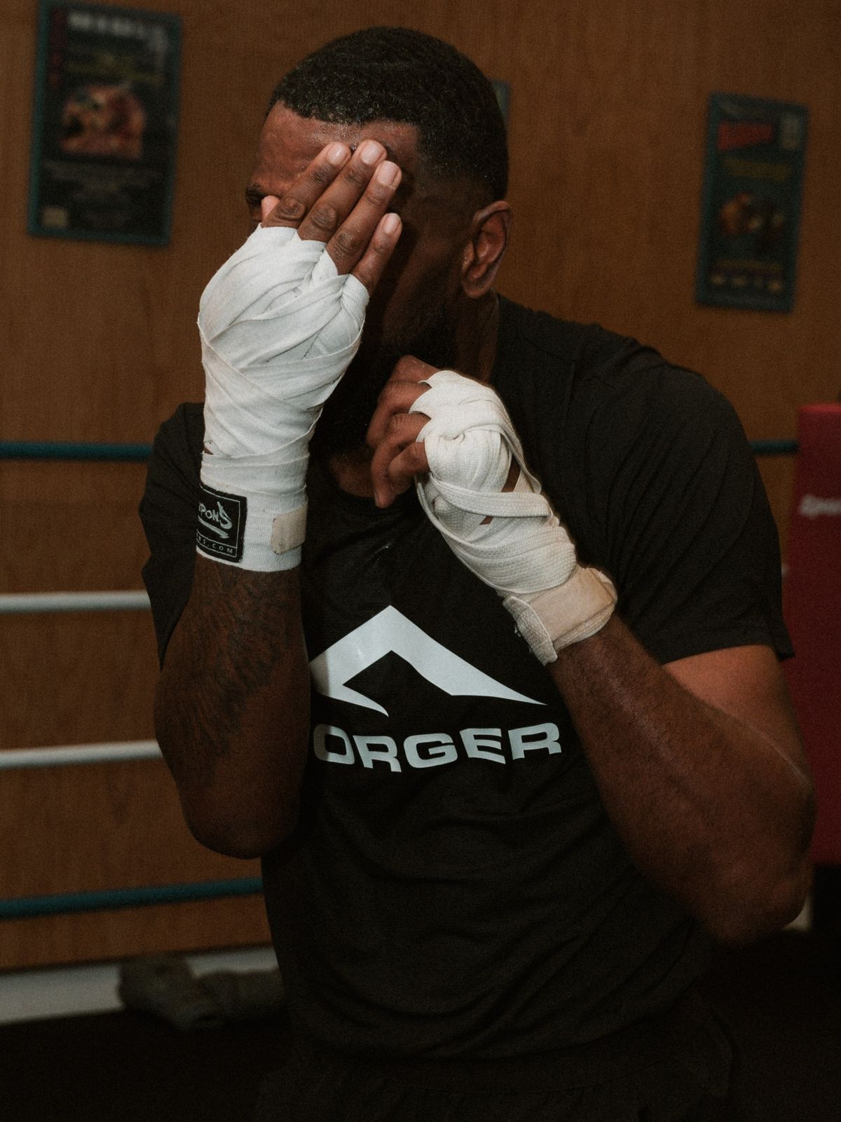 Boxeur FORGER mains bandées, t-shirt logo, près du ring.