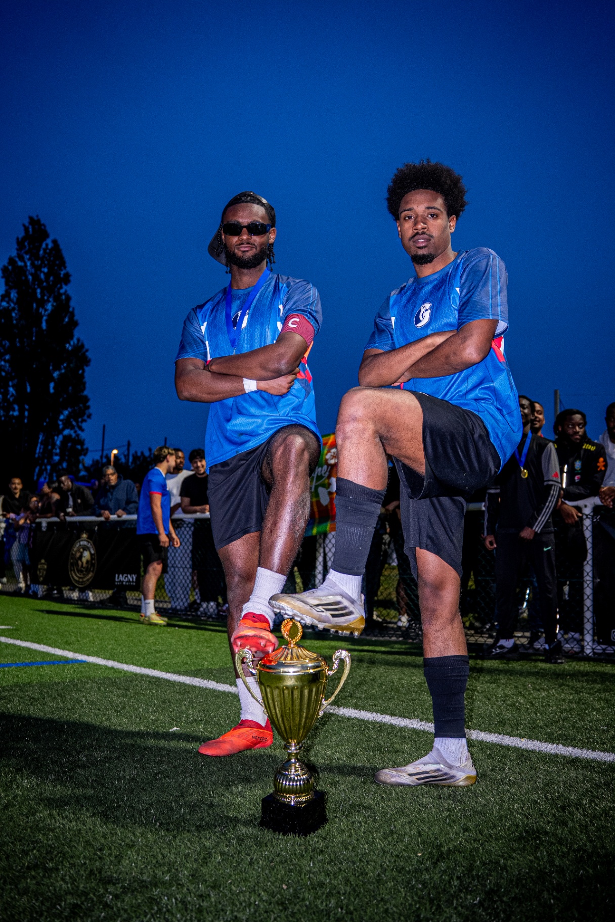Deux joueurs capitaines posant, pied sur le trophée